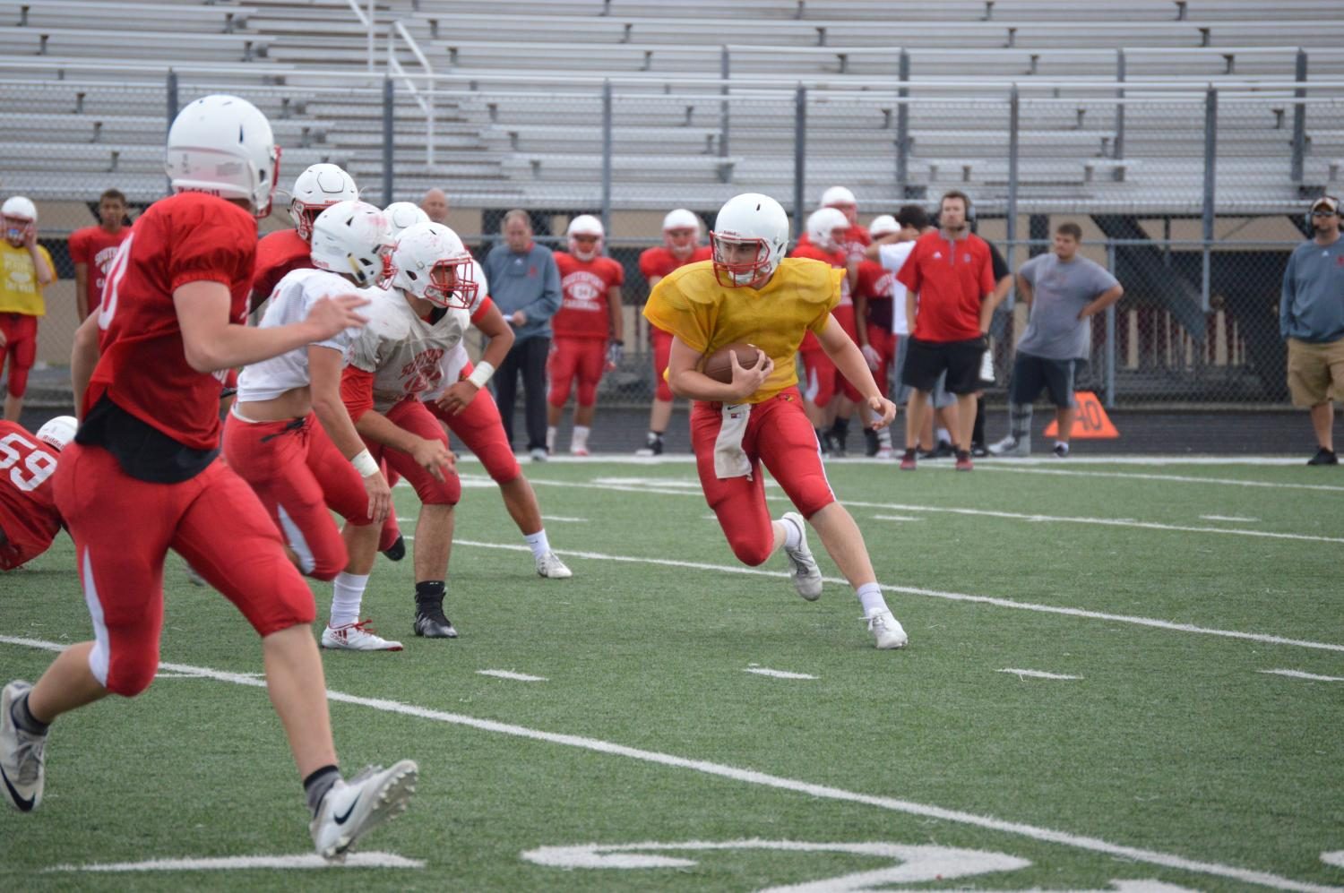 Junior Eddie Schott, in yellow, runs the ball up the field at the scrimmage game on Friday, Aug 4. Schott is beginning his second season as the SHS starting quarterback for the football team.