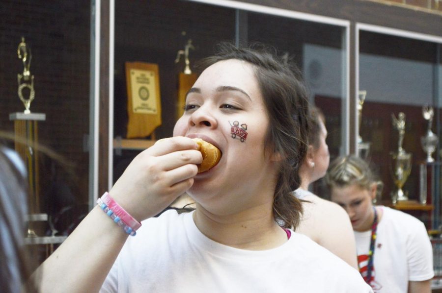 Senior Nathalia Garcia devours a hotdog grilled by English teacher Sam Hanley. He has helped serve food for multiple school events including tailgates and pre-parade parties.