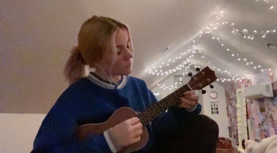 Junior Emma Meredith is practicing her ukulele. She likes to play it while singing.