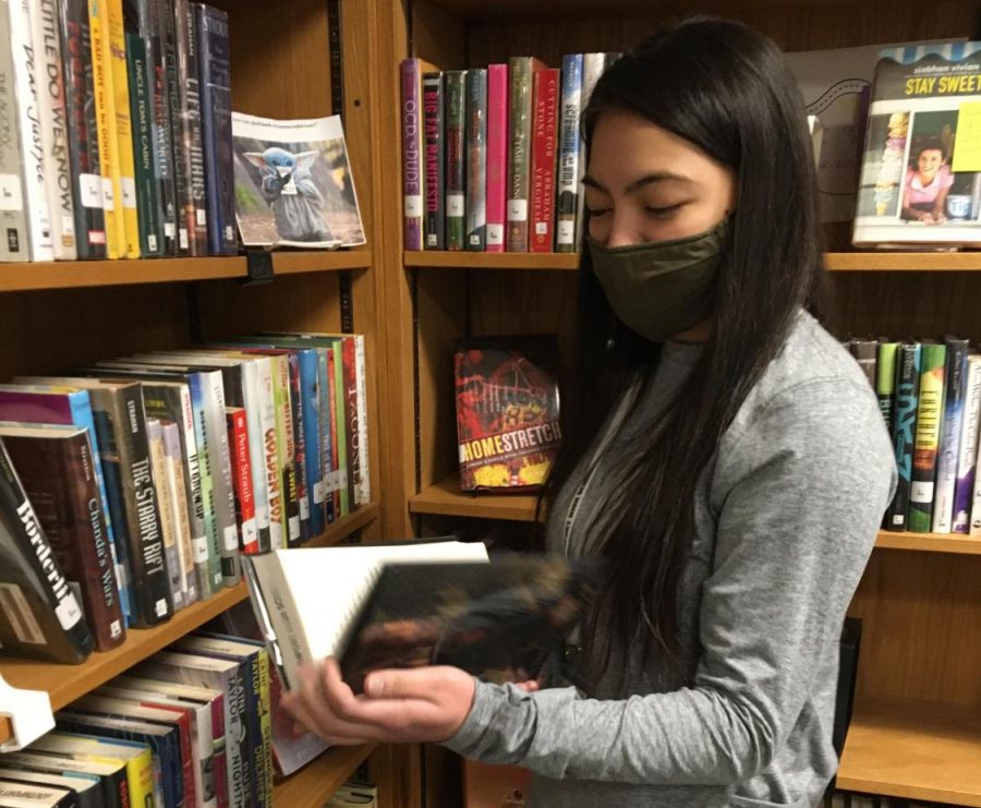 Junior Naomi Chan is helping out in the library. She enjoys reading instead of being on her phone.