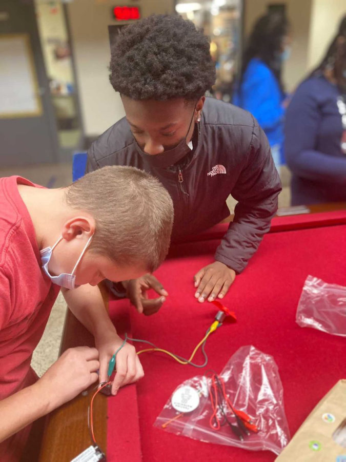 Senior Dante McDonald helps a younger member build a fan during a S.T.E.M. activity.
