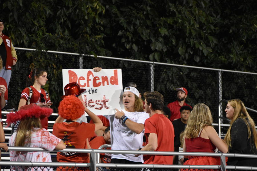 Junior Calvin Miller showing school spirit by holding up a Defend the Nest poster.