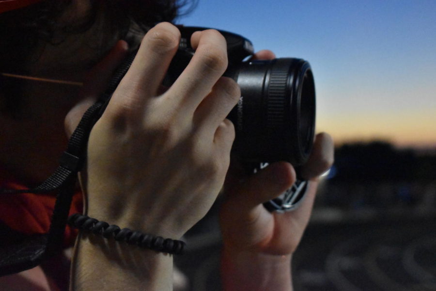 Junior Levi Smith holds up his camera at the Perry Meridian varsity football game. The Cards lost 7-36.