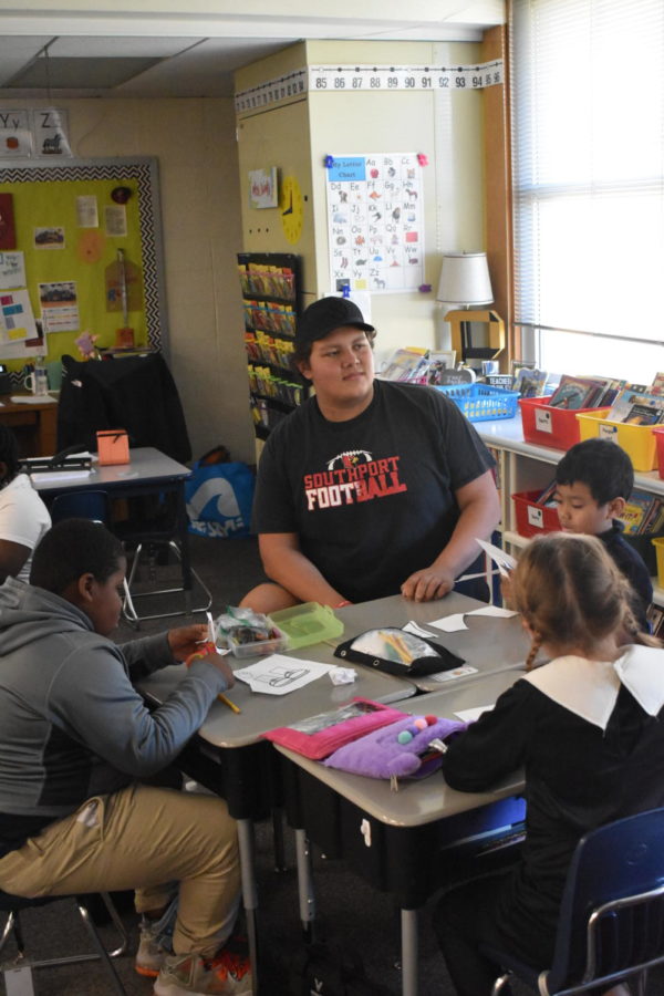 Junior Bo Lopez sits with second grade students at Homecroft Elementary on Oct. 28. Small groups of players go to several different elementary schools in the district each Friday.
