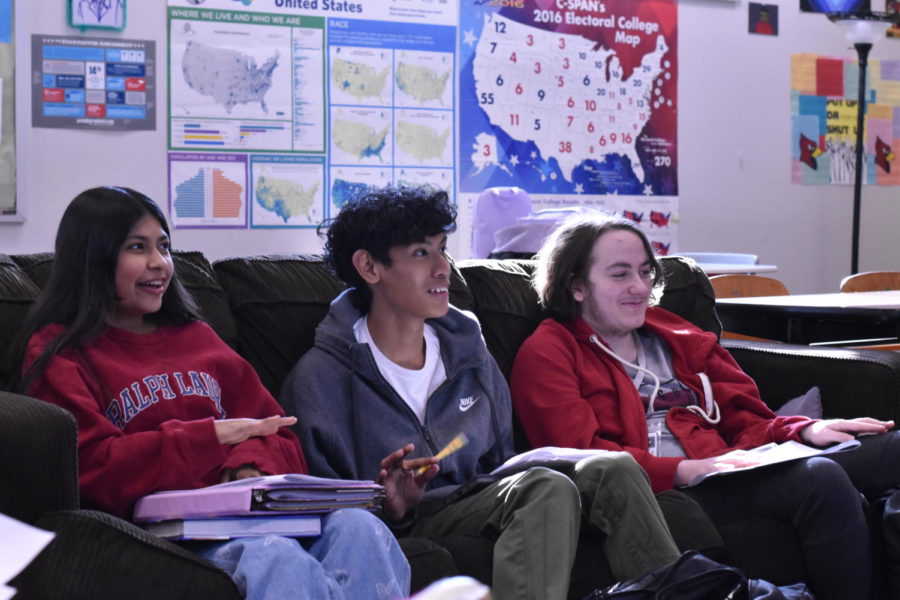 Seniors Jennifer Torres and Ulises Morales Gervacio and junior Jonah Gotkin sit and smile on the couch as Kevin Sanders conducts the Model U.N. meeting. The group meets each Monday and is open to all students. 