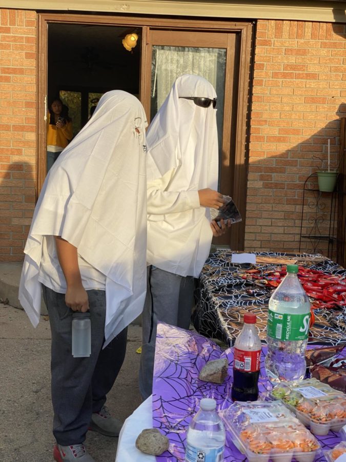 Two students dress up as ghosts to participate in the event on Oct 27. They stop by the snacks table to get candy.