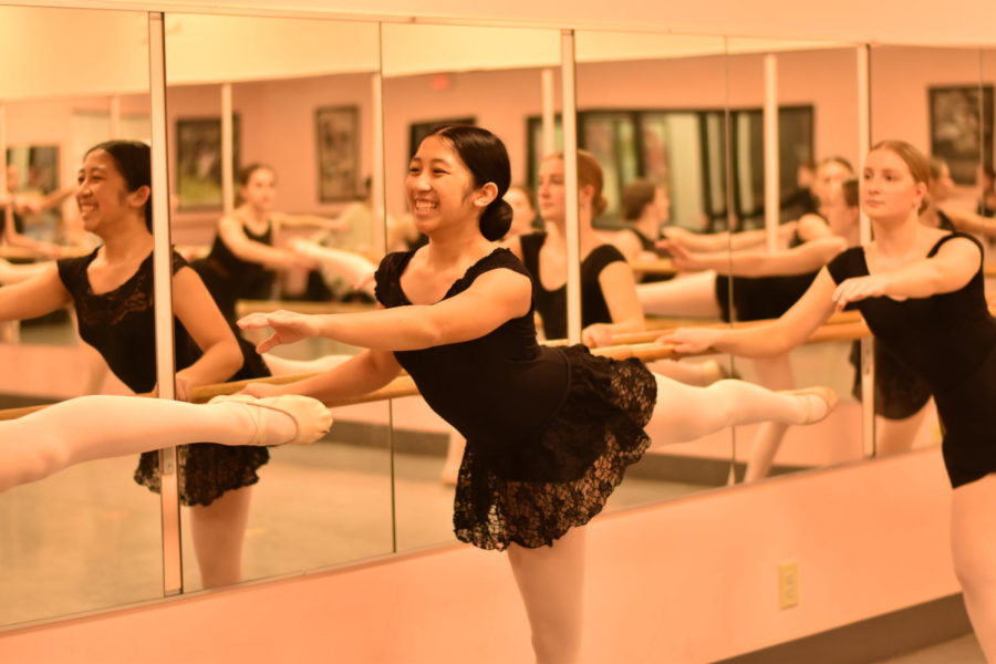 Sophomore Sofie Nool smiles as she extends her leg back at Tippy Toes Dance Studio on March 13.  She practiced holding onto the barre.