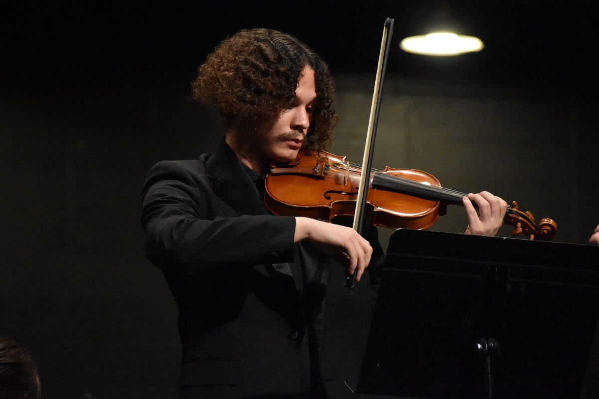 Junior Silas Denton stands while playing violin at orchestra concert on December 6. Denton has been playing the violin since he was 5 years old. 
photo by Darcy Leber
