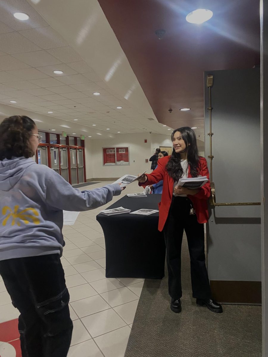 Junior volunteer, Zamantha Loza, passes out programs for visitors of the 8th grade scheduling parent night on Wednesday, Jan. 31.
photo by Lily Zing