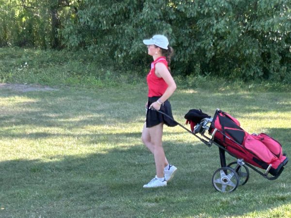 German exchange student, Adele Klussendorf, moves her bag along the fairway. This will be her first season playing on a high school team. (Photo contributed by Southport Athletics)