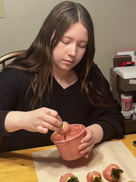 Sophomore Katie Crouch dips strawberries into icing. Crouch found her love from baking because of her family. photo by Kiley Bowman. 