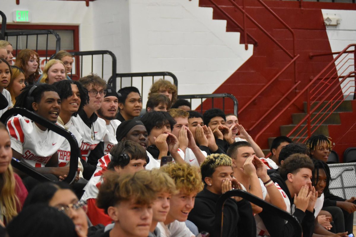 Students in the bleachers cheer for Moore during the hot dog eating contest. They chanted his nickname, which encouraged him to win the competition.