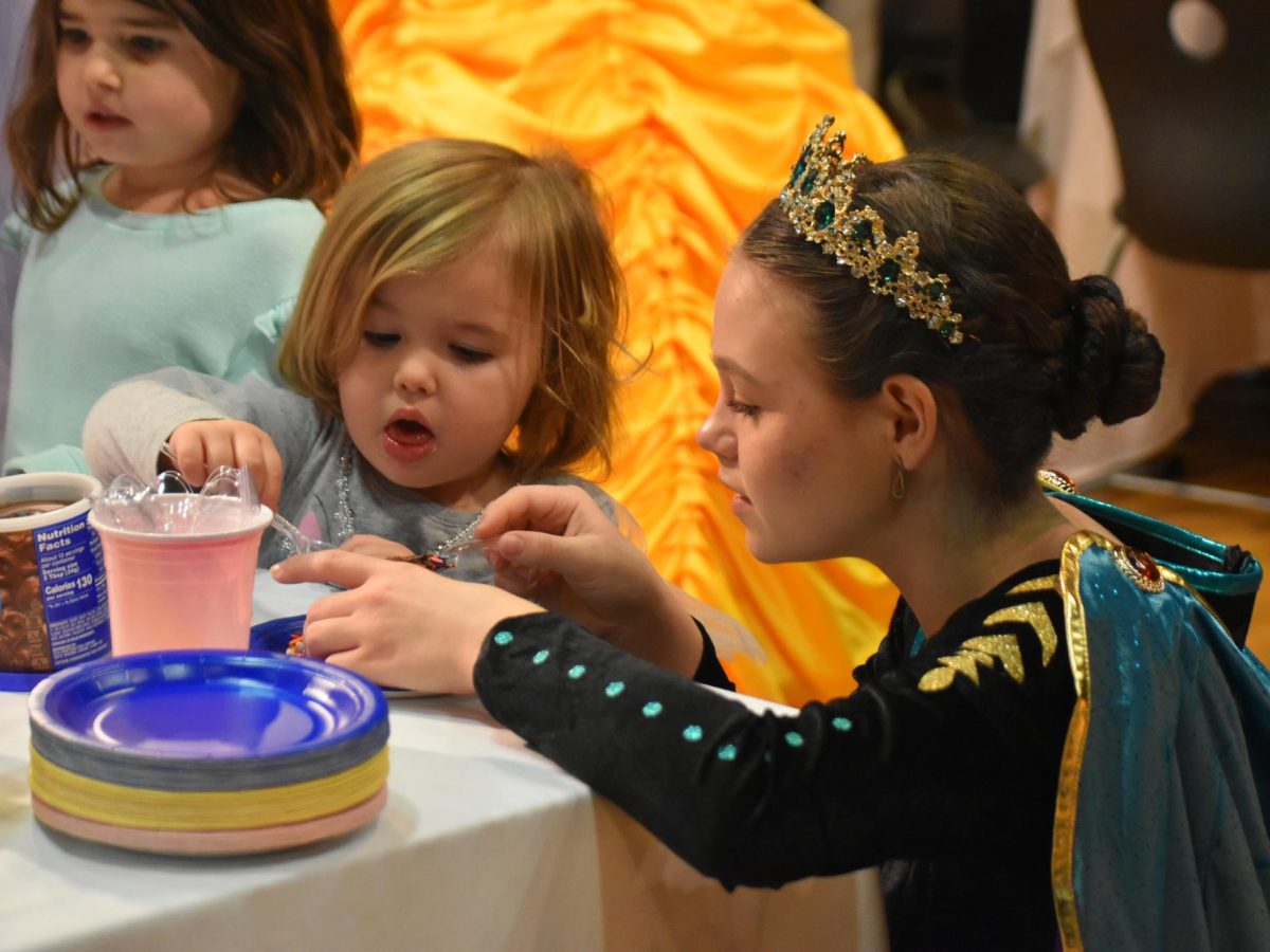Sophomore Anna LaBay assists one of the kids icing their sugar cookie. Afterwards, she helped put sprinkles on to avoid a mess.