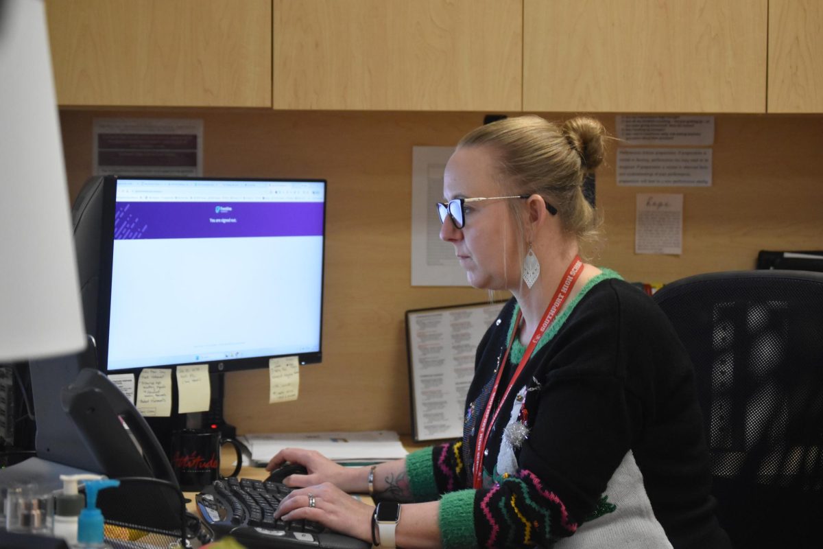 Amy Boone works at her desk at the end of her day on Dec. 11. She often ends her days by reading emails while her daughters stay in her office.