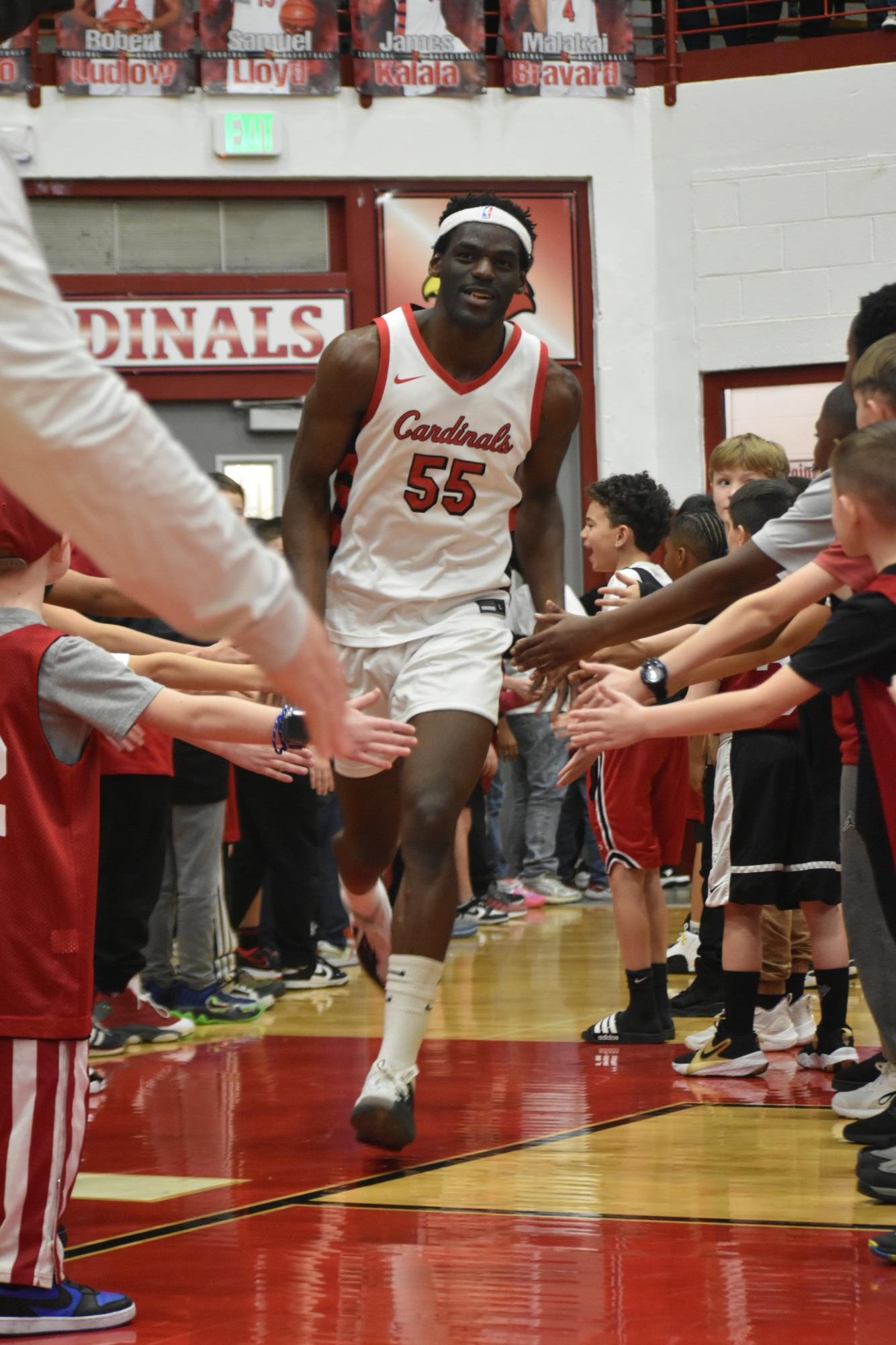 Senior James Kalala runs through a tunnel of youth players as he reaches the court. It was the annual "youth night" for the Cards. 