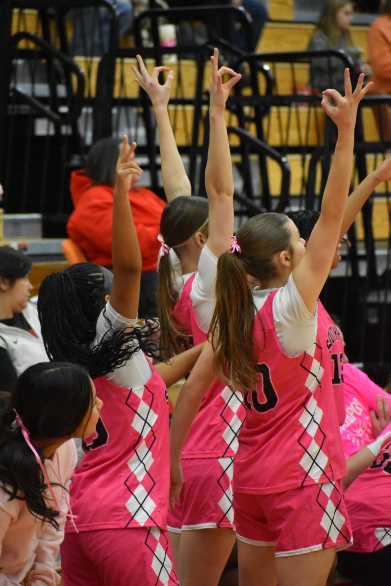 The SHS Lady Cards hold up three fingers as they watch the ball swish into the hoop, scoring an additional three points for the team.