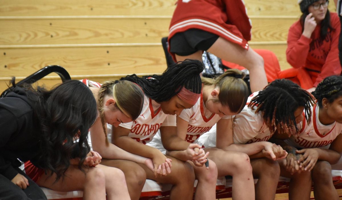 The Lady Cards interlock hands with one another as they recite a prayer, in hopes that their injured teammate, junior Lorelei Bennett gets back on her feet.