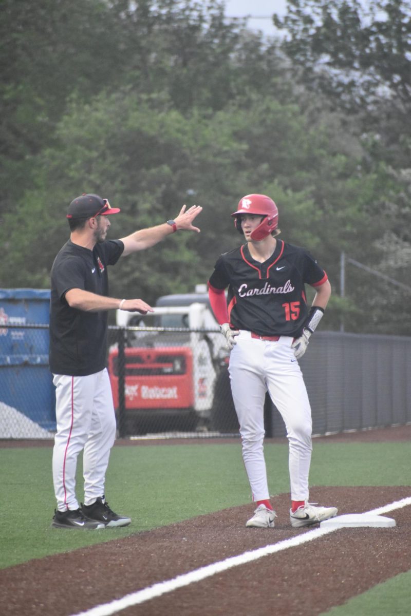 Junior Adam Watson and head coach Brendan Dudas converse about the next play while standing on third base.