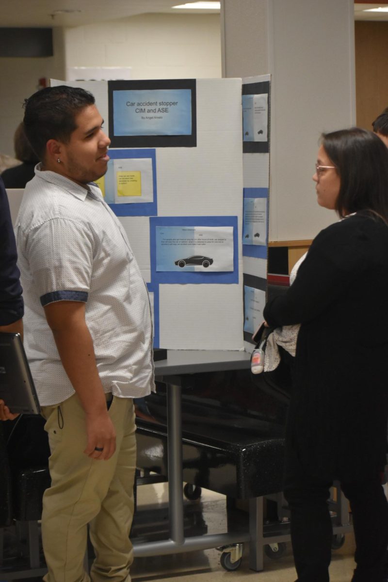 Senior Angel Arvelo talks to a guest at the Night of Engineering about his project. His project was about an idea to stop car accidents.